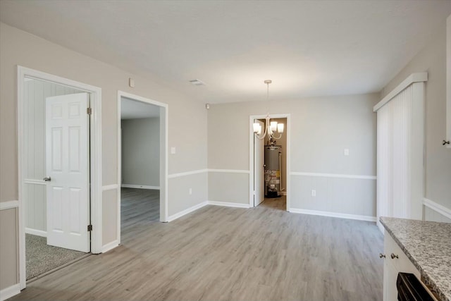 unfurnished dining area with gas water heater, light hardwood / wood-style flooring, and an inviting chandelier