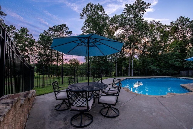 295 River Wind Dr, North Augusta, SC 29841 - pool at dusk with a patio area, view of wooded area, and outdoor dining area