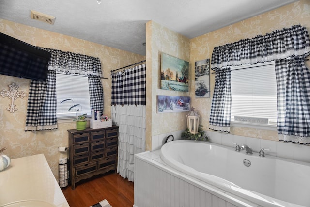 bathroom with vanity, wood-type flooring, a textured ceiling, and plus walk in shower