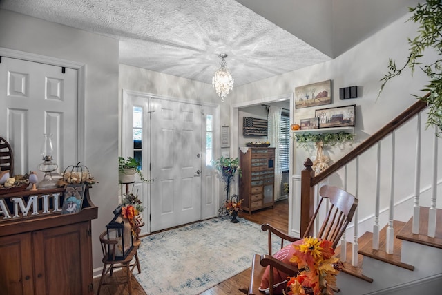 foyer featuring a textured ceiling, a notable chandelier, and hardwood / wood-style flooring