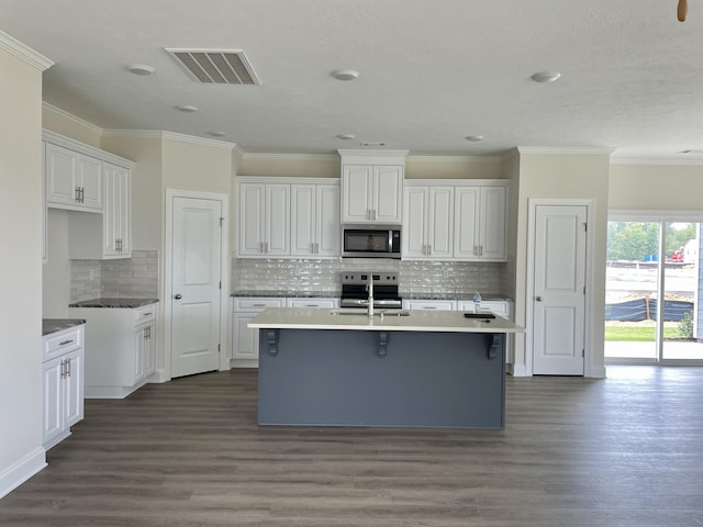 kitchen featuring white cabinets, a kitchen island with sink, appliances with stainless steel finishes, and dark wood-type flooring