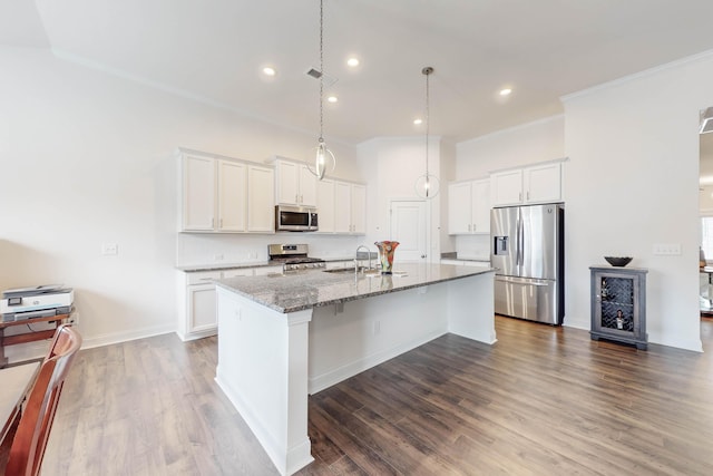 kitchen featuring white cabinets, stone countertops, an island with sink, and appliances with stainless steel finishes