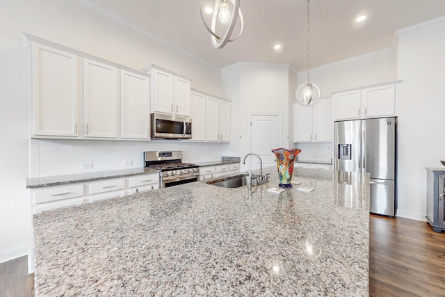 kitchen featuring sink, white cabinets, hanging light fixtures, and appliances with stainless steel finishes