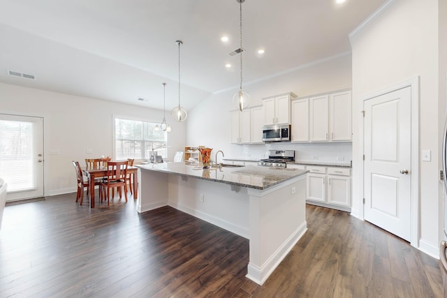 kitchen featuring white cabinets, stainless steel appliances, a kitchen island with sink, and hanging light fixtures