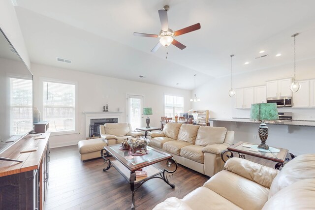 living room featuring ceiling fan, dark hardwood / wood-style floors, and vaulted ceiling