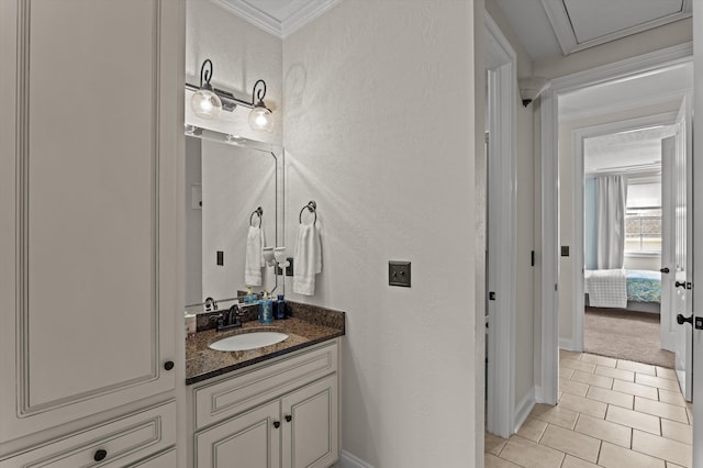 bathroom featuring tile patterned flooring, vanity, a textured wall, crown molding, and baseboards