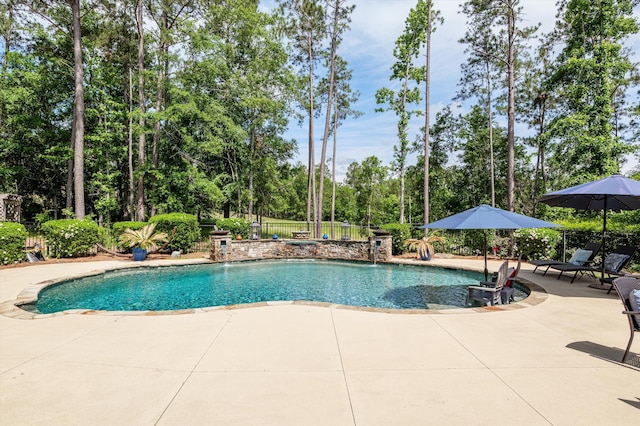 view of swimming pool featuring a patio, fence, and view of scattered trees