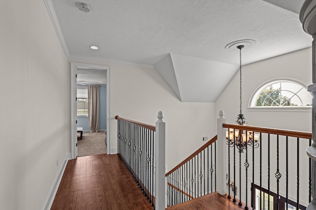 hallway featuring a chandelier, an upstairs landing, a textured ceiling, wood finished floors, and baseboards