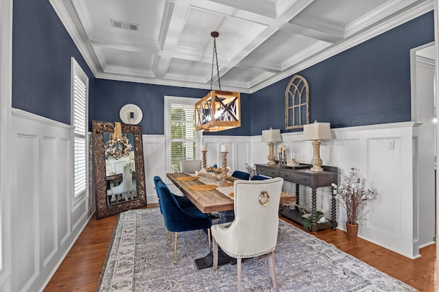 dining area with a decorative wall, a wainscoted wall, beamed ceiling, wood finished floors, and a fireplace