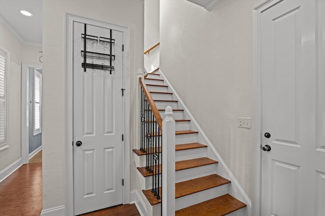 stairway with wood finished floors, baseboards, and ornamental molding