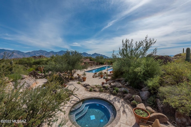 view of pool featuring a patio, a mountain view, and an in ground hot tub