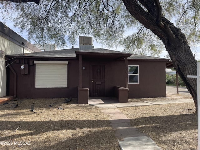 rear view of house with central air condition unit, roof with shingles, and stucco siding