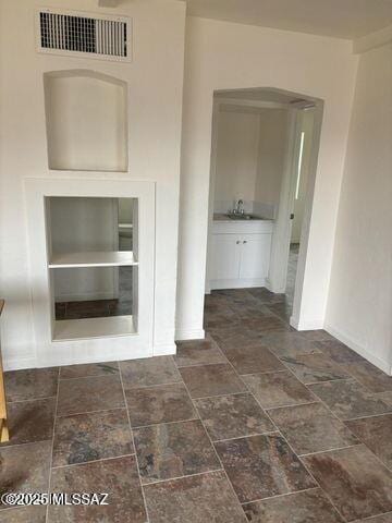 interior space featuring visible vents, stone finish floor, baseboards, and a sink