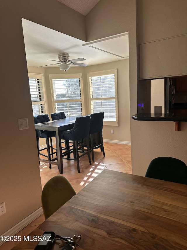 tiled dining space with ceiling fan and vaulted ceiling