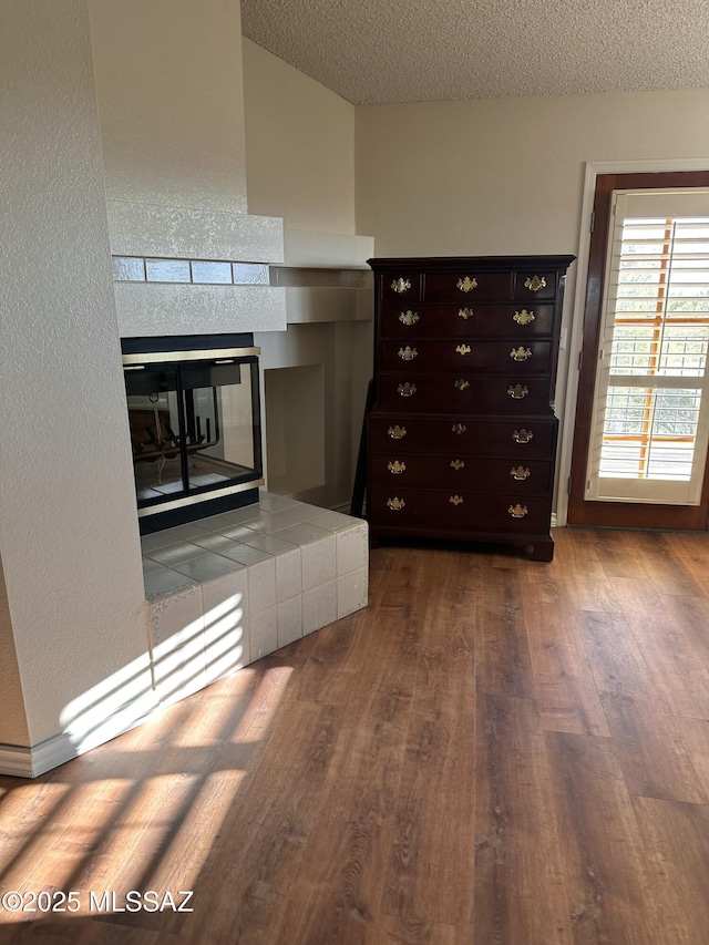 kitchen with a textured ceiling, a fireplace, dark brown cabinets, and hardwood / wood-style floors