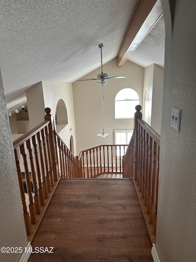 hallway with hardwood / wood-style floors, lofted ceiling with beams, and a textured ceiling