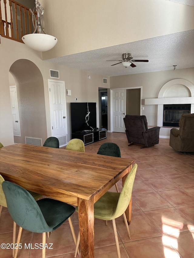 dining area featuring ceiling fan, a textured ceiling, and tile patterned flooring