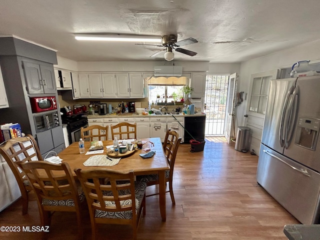 dining space with ceiling fan, light hardwood / wood-style flooring, and sink