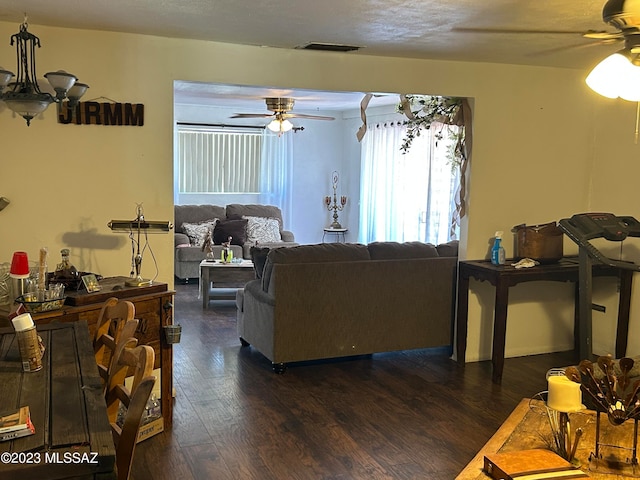 living room featuring dark wood-type flooring and ceiling fan with notable chandelier