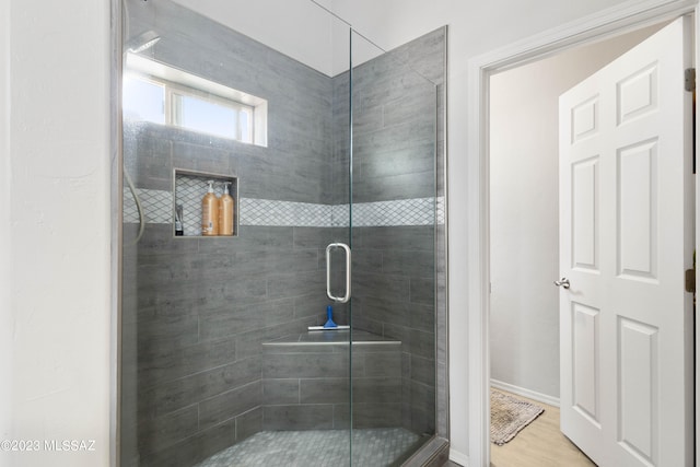 bathroom featuring a shower with shower door and wood-type flooring