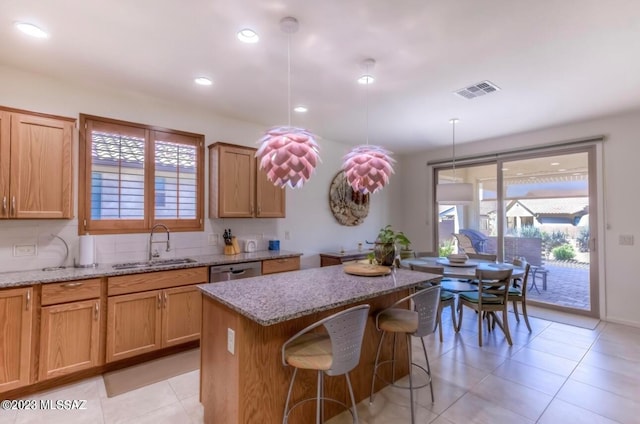 kitchen featuring hanging light fixtures, a kitchen island, a kitchen bar, light tile floors, and light stone countertops