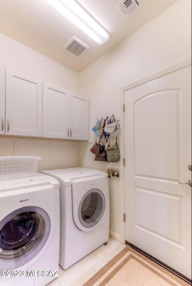 laundry room featuring light tile floors, cabinets, and independent washer and dryer