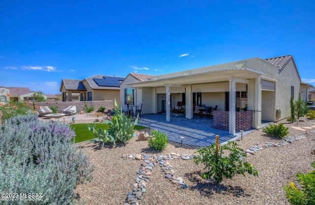 rear view of house with solar panels and a patio area