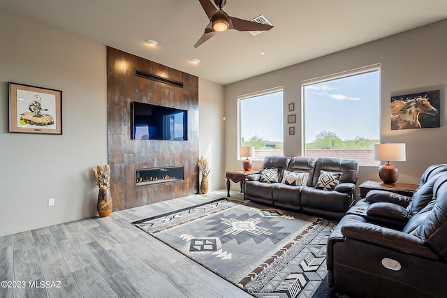 living room with ceiling fan, a tile fireplace, and dark hardwood / wood-style floors