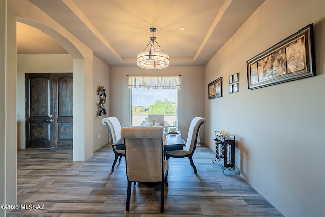 dining space with dark hardwood / wood-style floors and a tray ceiling