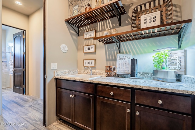 interior space with light stone countertops, dark brown cabinets, light hardwood / wood-style floors, and sink