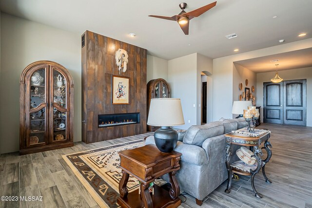 living room with a tiled fireplace, light hardwood / wood-style floors, and ceiling fan