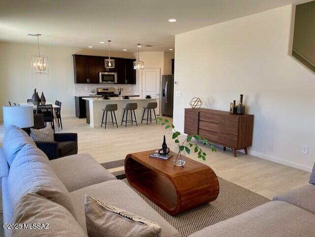 living room with an inviting chandelier and light wood-type flooring