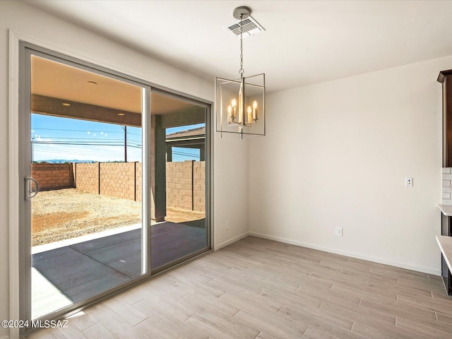 unfurnished dining area with an inviting chandelier and light hardwood / wood-style floors