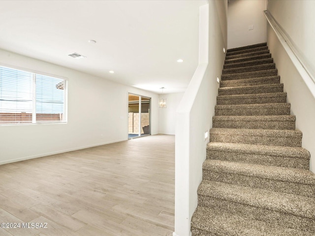 staircase featuring a chandelier, hardwood / wood-style floors, and a wealth of natural light