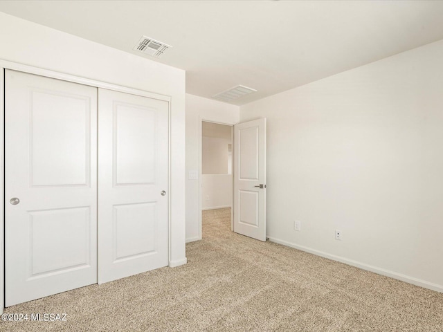 unfurnished bedroom with light carpet and a closet