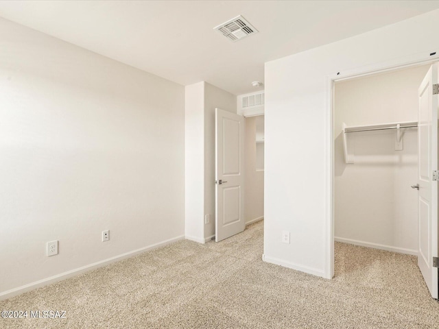 unfurnished bedroom featuring a walk in closet, light carpet, and a closet