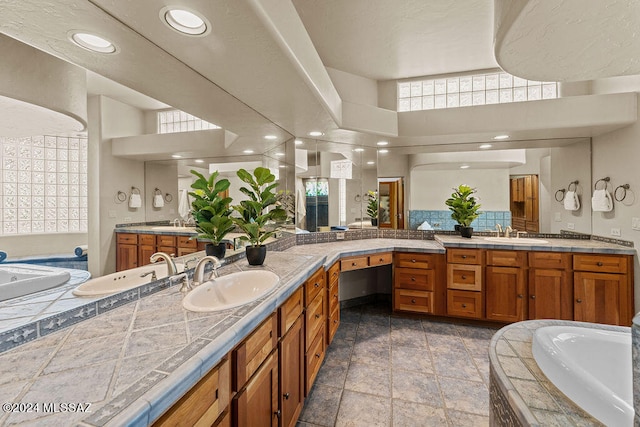 bathroom featuring a towering ceiling, tiled bath, vanity, and tile floors