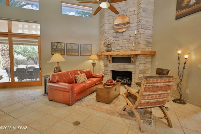 living room featuring a towering ceiling, ceiling fan, tile floors, and a fireplace