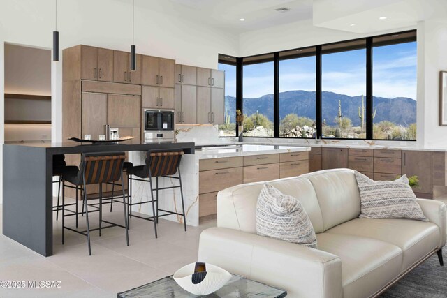 kitchen featuring a mountain view, a center island, light tile patterned floors, and sink