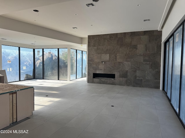 unfurnished living room featuring a fireplace, light tile patterned floors, and tile walls