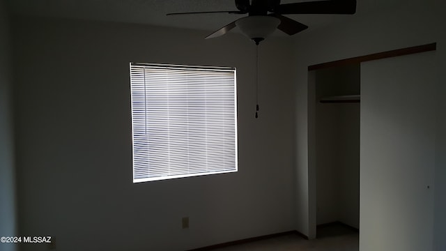 unfurnished bedroom with ceiling fan and a closet