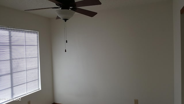 unfurnished room with ceiling fan and a textured ceiling