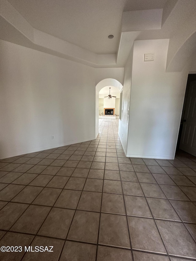 empty room featuring a tray ceiling and light tile floors