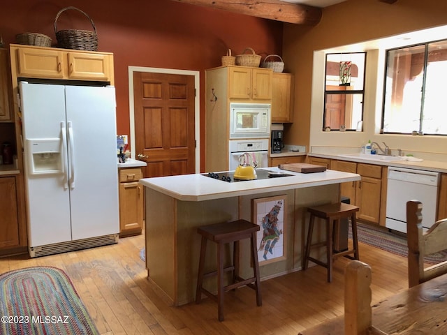 kitchen with beam ceiling, white appliances, a center island, light wood-type flooring, and a kitchen bar