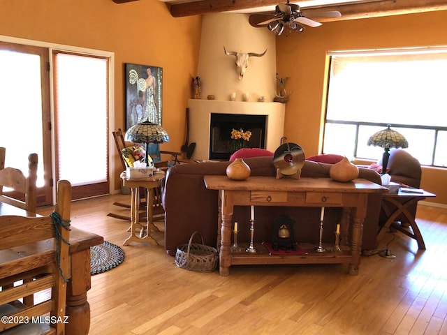 living room featuring ceiling fan, light wood-type flooring, and beam ceiling