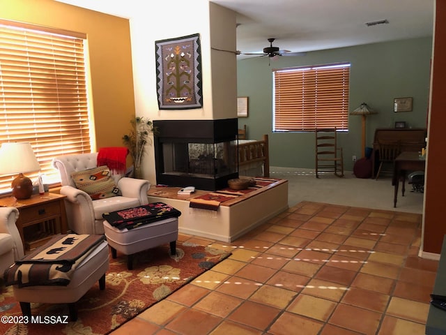 living room with ceiling fan, a multi sided fireplace, and tile patterned floors