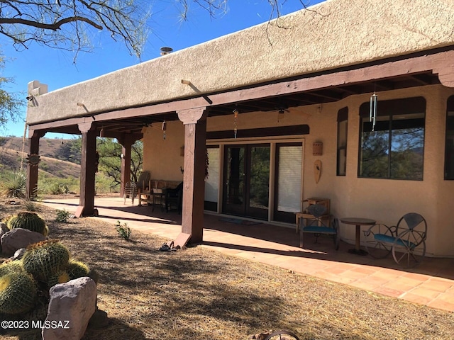 back of property with ceiling fan and a patio