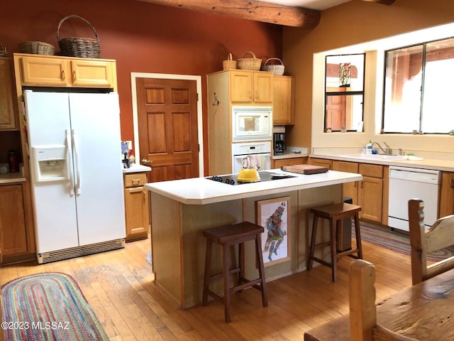 kitchen featuring beam ceiling, white appliances, a kitchen island, light wood-type flooring, and a kitchen bar