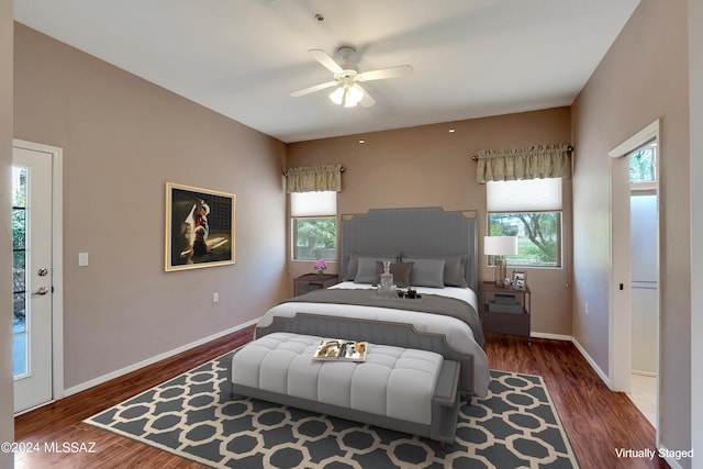 bedroom with multiple windows, dark wood-type flooring, access to exterior, and ceiling fan