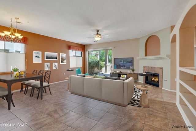 living room with ceiling fan with notable chandelier, a tile fireplace, and light tile patterned floors